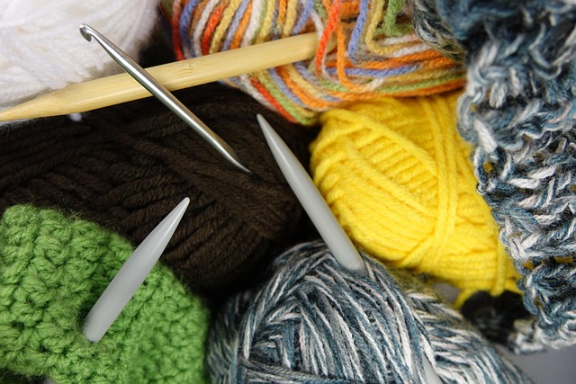 various multi-coloured yarn with crochet hooks and knitting needles on them
